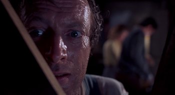 Movie still from “Evil Dead II” (1987), directed by Sam Raimi – A man's face while holding a wooden stick; Close Up shot, Low angle