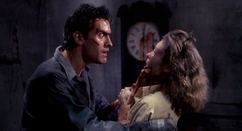 Movie still from “Evil Dead II” (1987), directed by Sam Raimi – A man and a woman fighting in front of a wall clock; Medium shot, Over the shoulder angle