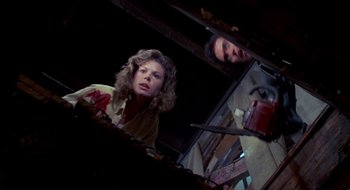 Movie still from “Evil Dead II” (1987), directed by Sam Raimi – A woman standing next to a man in a dark room; Medium shot, Overhead angle