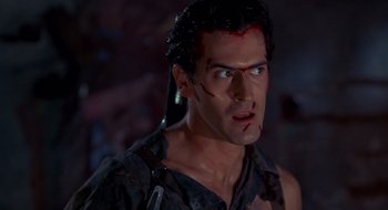 Movie still from “Evil Dead II” (1987), directed by Sam Raimi – A person with a knife on his face; Close Up shot, Over the shoulder angle