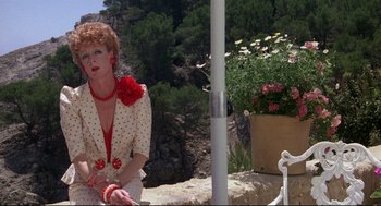 Movie still from “Evil Under the Sun” (1982), directed by Guy Hamilton – A woman sitting on top of a rock next to a fountain; Medium shot, Low angle