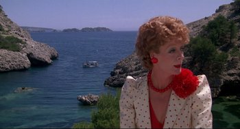 Movie still from “Evil Under the Sun” (1982), directed by Guy Hamilton – A woman standing on top of a hill next to a body of water; Close Up shot, Over the shoulder angle