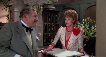 Movie still from “Evil Under the Sun” (1982), directed by Guy Hamilton – An older man and woman sitting at a table talking; Medium shot, Over the shoulder angle