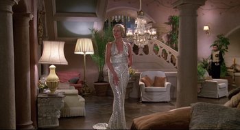 Movie still from “Evil Under the Sun” (1982), directed by Guy Hamilton – A woman in a silver dress standing in a living room; Wide shot, Low angle