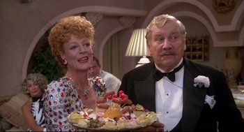 Movie still from “Evil Under the Sun” (1982), directed by Guy Hamilton – An older man and woman holding a tray of food; Medium shot, Over the shoulder angle