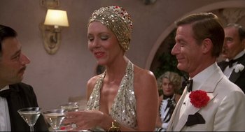 Movie still from “Evil Under the Sun” (1982), directed by Guy Hamilton – A man and a woman wearing a sequined headpiece; Medium shot, Over the shoulder angle
