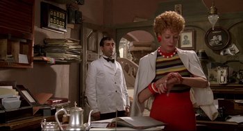 Movie still from “Evil Under the Sun” (1982), directed by Guy Hamilton – A man and a woman standing in front of a table; Medium shot, Low angle