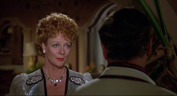 Movie still from “Evil Under the Sun” (1982), directed by Guy Hamilton – An older woman wearing a necklace and looking at a younger man; Close Up shot, Over the shoulder angle