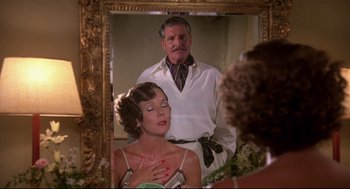 Movie still from “Evil Under the Sun” (1982), directed by Guy Hamilton – An older man standing in front of an older woman in front of a mirror; Medium shot, Over the shoulder angle