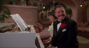 Movie still from “Evil Under the Sun” (1982), directed by Guy Hamilton – A man and a woman sitting in front of a white piano; Medium shot, Low angle