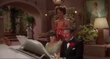 Movie still from “Evil Under the Sun” (1982), directed by Guy Hamilton – Two women and a man sitting at a piano; Medium shot, High angle