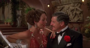 Movie still from “Evil Under the Sun” (1982), directed by Guy Hamilton – An older man and a younger woman in formal wear; Close Up shot, Over the shoulder angle