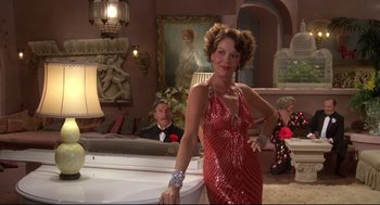Movie still from “Evil Under the Sun” (1982), directed by Guy Hamilton – A woman in a red dress standing in front of a man in a tuxedo; Medium shot, Low angle