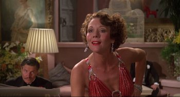 Movie still from “Evil Under the Sun” (1982), directed by Guy Hamilton – A woman in a red dress sitting in front of a lamp; Close Up shot, Low angle