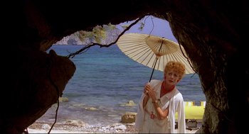 Movie still from “Evil Under the Sun” (1982), directed by Guy Hamilton – An older woman holding an umbrella near the ocean; Wide shot, Low angle
