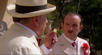 Movie still from “Evil Under the Sun” (1982), directed by Guy Hamilton – Two men in suits and hats are holding a coin; Close Up shot, Over the shoulder angle