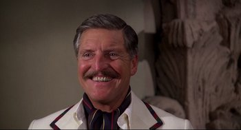 Movie still from “Evil Under the Sun” (1982), directed by Guy Hamilton – An older man with a mustache smiling for the camera; Close Up shot, Low angle