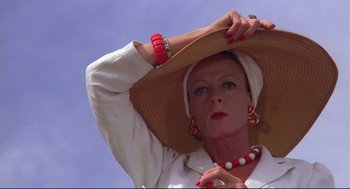 Movie still from “Evil Under the Sun” (1982), directed by Guy Hamilton – A woman in a hat and a white shirt is posing for a picture; Close Up shot, Low angle