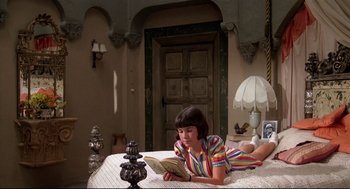 Movie still from “Evil Under the Sun” (1982), directed by Guy Hamilton – A woman reading a book on a bed; Wide shot, High angle