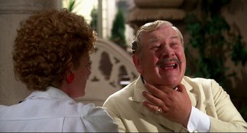 Movie still from “Evil Under the Sun” (1982), directed by Guy Hamilton – An older man and a woman are laughing together; Close Up shot, Over the shoulder angle