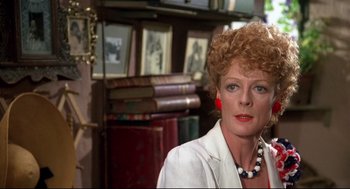 Movie still from “Evil Under the Sun” (1982), directed by Guy Hamilton – An older woman in a white shirt and red necklace; Close Up shot, Over the shoulder angle