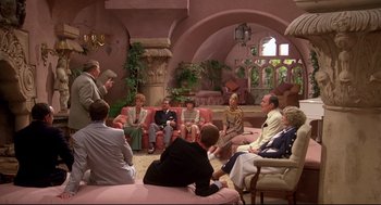 Movie still from “Evil Under the Sun” (1982), directed by Guy Hamilton – A group of people sitting in a living room talking; Wide shot, High angle