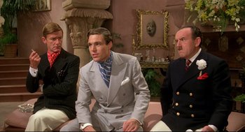 Movie still from “Evil Under the Sun” (1982), directed by Guy Hamilton – A group of men sitting next to each other on the ground; Medium shot, Low angle