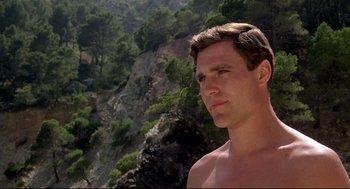 Movie still from “Evil Under the Sun” (1982), directed by Guy Hamilton – A young man standing on top of a mountain; Close Up shot, Low angle