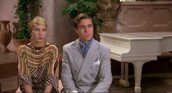Movie still from “Evil Under the Sun” (1982), directed by Guy Hamilton – A man and a woman sitting next to each other in front of a white piano; Medium shot, Low angle