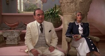 Movie still from “Evil Under the Sun” (1982), directed by Guy Hamilton – An older man and woman sitting on a couch; Medium shot, Over the shoulder angle