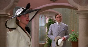 Movie still from “Evil Under the Sun” (1982), directed by Guy Hamilton – A man and a woman wearing hats in a room; Medium shot, Low angle