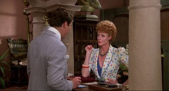 Movie still from “Evil Under the Sun” (1982), directed by Guy Hamilton – A man and a woman sitting at a table talking to each other; Medium shot, Over the shoulder angle