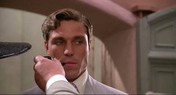Movie still from “Evil Under the Sun” (1982), directed by Guy Hamilton – A man in a suit and tie holding a cell phone to his ear; Close Up shot, Low angle