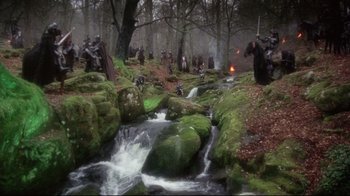 Movie still from “Excalibur” (1981), directed by John Boorman – A group of people standing next to each other in the woods; Extreme Wide shot, High angle