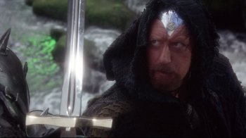 Movie still from “Excalibur” (1981), directed by John Boorman – A person holding a sword; Medium shot, Over the shoulder angle