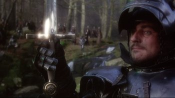 Movie still from “Excalibur” (1981), directed by John Boorman – A man holding a sword in front of a group of people; Close Up shot, Over the shoulder angle
