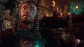 Movie still from “Excalibur” (1981), directed by John Boorman – A person wearing a chain mail armor; Close Up shot, Over the shoulder angle