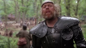 Movie still from “Excalibur” (1981), directed by John Boorman – A man in a helmet and armor standing in the woods; Close Up shot, Over the shoulder angle