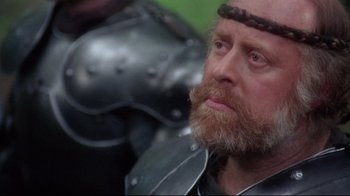 Movie still from “Excalibur” (1981), directed by John Boorman – A person wearing a helmet; Close Up shot, Over the shoulder angle