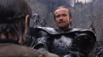 Movie still from “Excalibur” (1981), directed by John Boorman – A man wearing a suit of armor in a castle; Close Up shot, Over the shoulder angle