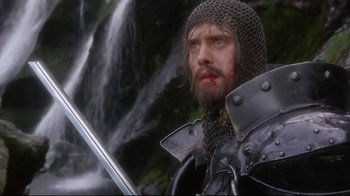 Movie still from “Excalibur” (1981), directed by John Boorman – A person with a sword; Close Up shot, Low angle