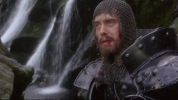 Movie still from “Excalibur” (1981), directed by John Boorman – A person wearing a chain mail armor; Close Up shot, Low angle