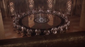 Movie still from “Excalibur” (1981), directed by John Boorman – A group of people sitting around a round table; Extreme Wide shot, High angle