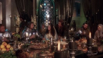 Movie still from “Excalibur” (1981), directed by John Boorman – A group of people sitting at a table with food on it; Wide shot, High angle