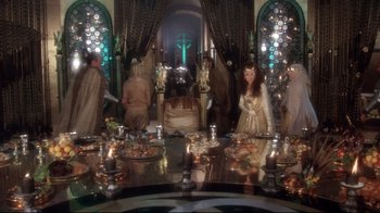 Movie still from “Excalibur” (1981), directed by John Boorman – A group of people standing around a dining table; Wide shot, High angle