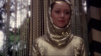 Movie still from “Excalibur” (1981), directed by John Boorman – A woman wearing a gold dress and a scarf around her neck; Close Up shot, Low angle