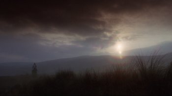 Movie still from “Excalibur” (1981), directed by John Boorman – The sun is setting in the dark sky over the mountains; Extreme Wide shot, Low angle