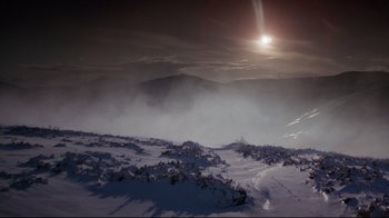 Movie still from “Excalibur” (1981), directed by John Boorman – The sun is shining over a snowy mountain; Extreme Wide shot, High angle