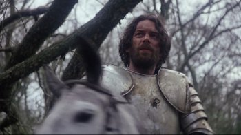 Movie still from “Excalibur” (1981), directed by John Boorman – A person wearing a suit of armor; Medium shot, Low angle