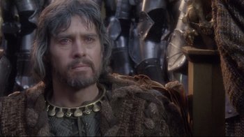 Movie still from “Excalibur” (1981), directed by John Boorman – A person with a beard wearing a costume; Close Up shot, Over the shoulder angle